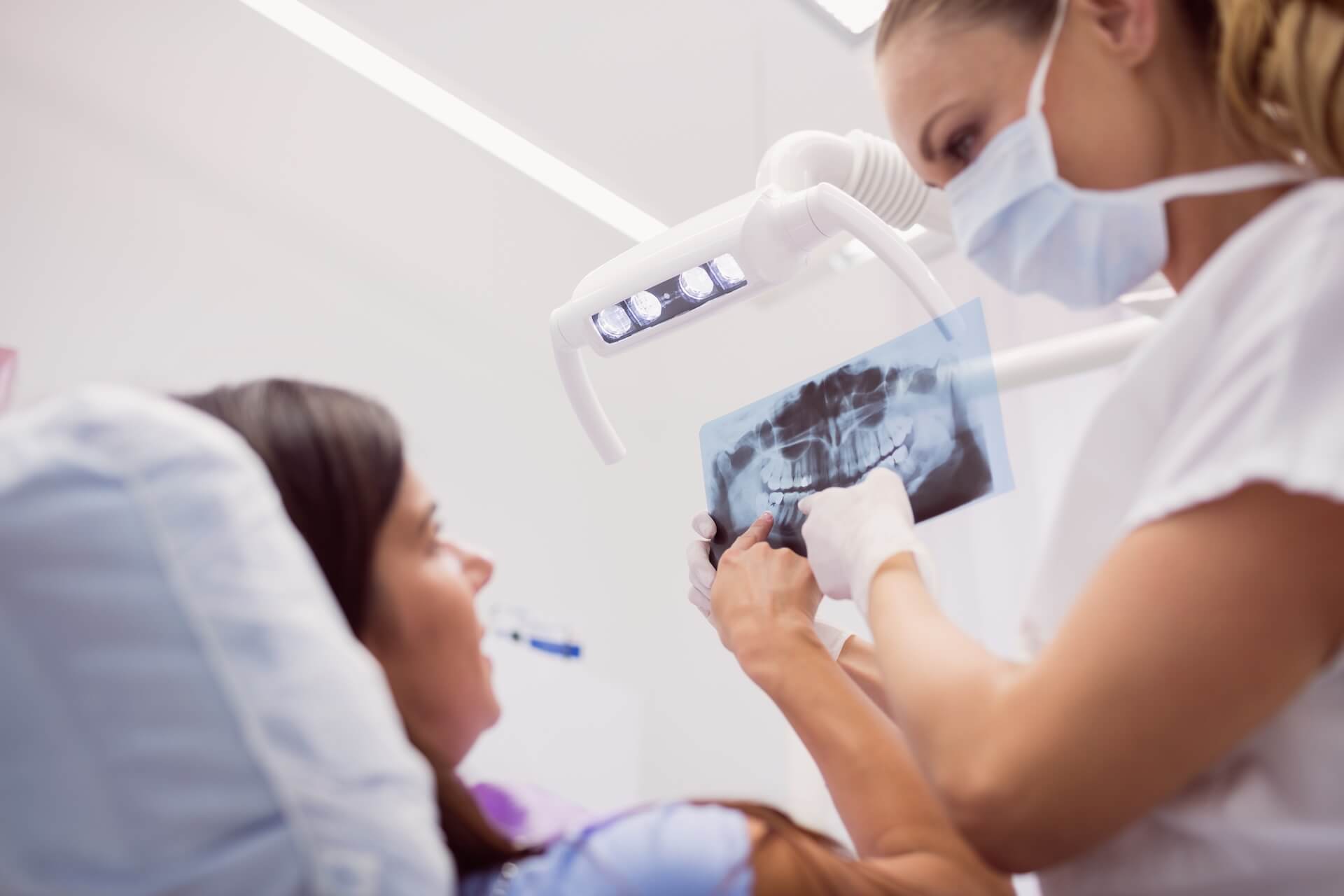 Dentysta pokazuje pacjentowi zdjecie rentgenowskie